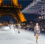 Models walking a nighttime runway in front of the Eiffel Tower during a Paris fashion show