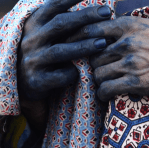 Indigo-stained hands holding traditional patterned fabric